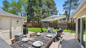 Une terrasse extérieure avec une table en bois mise pour le repas, entourée de fauteuils Adirondack.