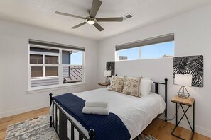 A bedroom with a bed, a ceiling fan, two bedside tables, and a window with blinds. - Old Town Getaway Free Bikes & Private Balconies (Fort Collins)