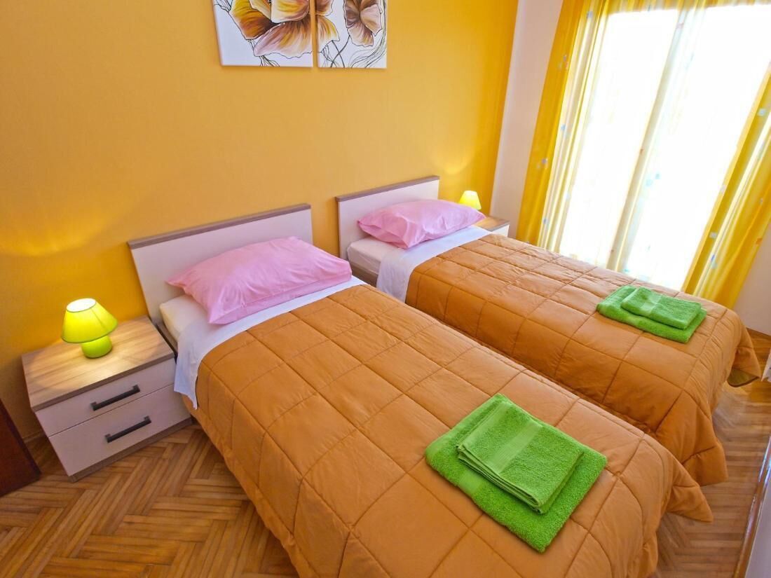 A hotel room with two beds, a nightstand with a lamp, and a painting on the wall.