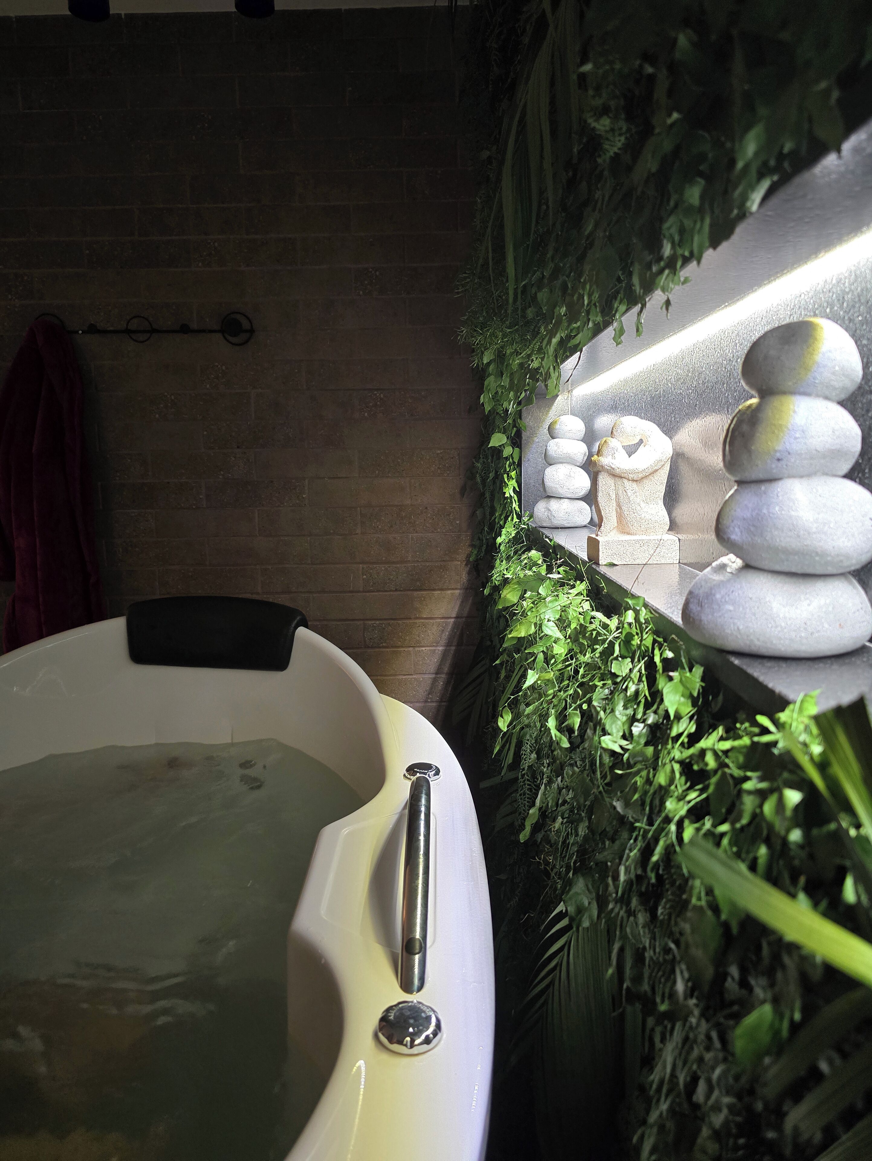 A spa area with a hot tub, a stone arrangement, and a brick wall.