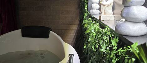 A spa area with a hot tub, a stone arrangement, and a brick wall.