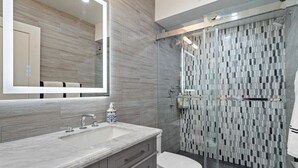 A modern bathroom with a marble sink, a glass shower enclosure, and a tiled shower wall. - BE FIRST TO STAY at The Camelback Retreat in Scottsdale (Scottsdale)