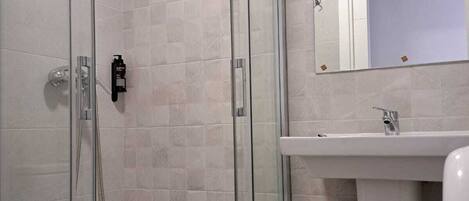 A modern bathroom with a glass-enclosed shower, a white sink, and a mirror above the sink.
