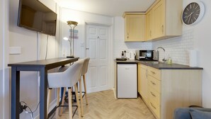Una cocina moderna con televisor de pantalla plana, cafetera y microondas.