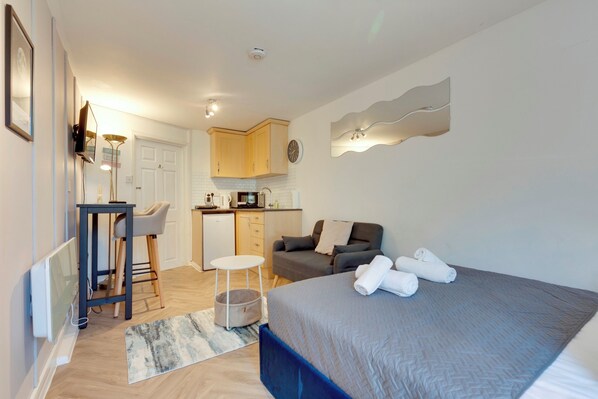 A compact hotel room with a bed, a small kitchenette, a dining area, and a bathroom. - Pass the Keys | Stylish and modern apartment (Cambridge)