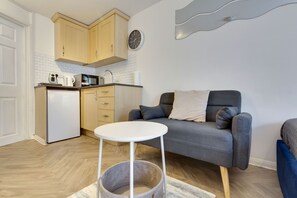 A compact living space with a kitchenette, a grey sofa, and a small white table. - Pass the Keys | Stylish and modern apartment (Cambridge)