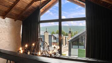 A room with a large window overlooking a mountainous landscape.