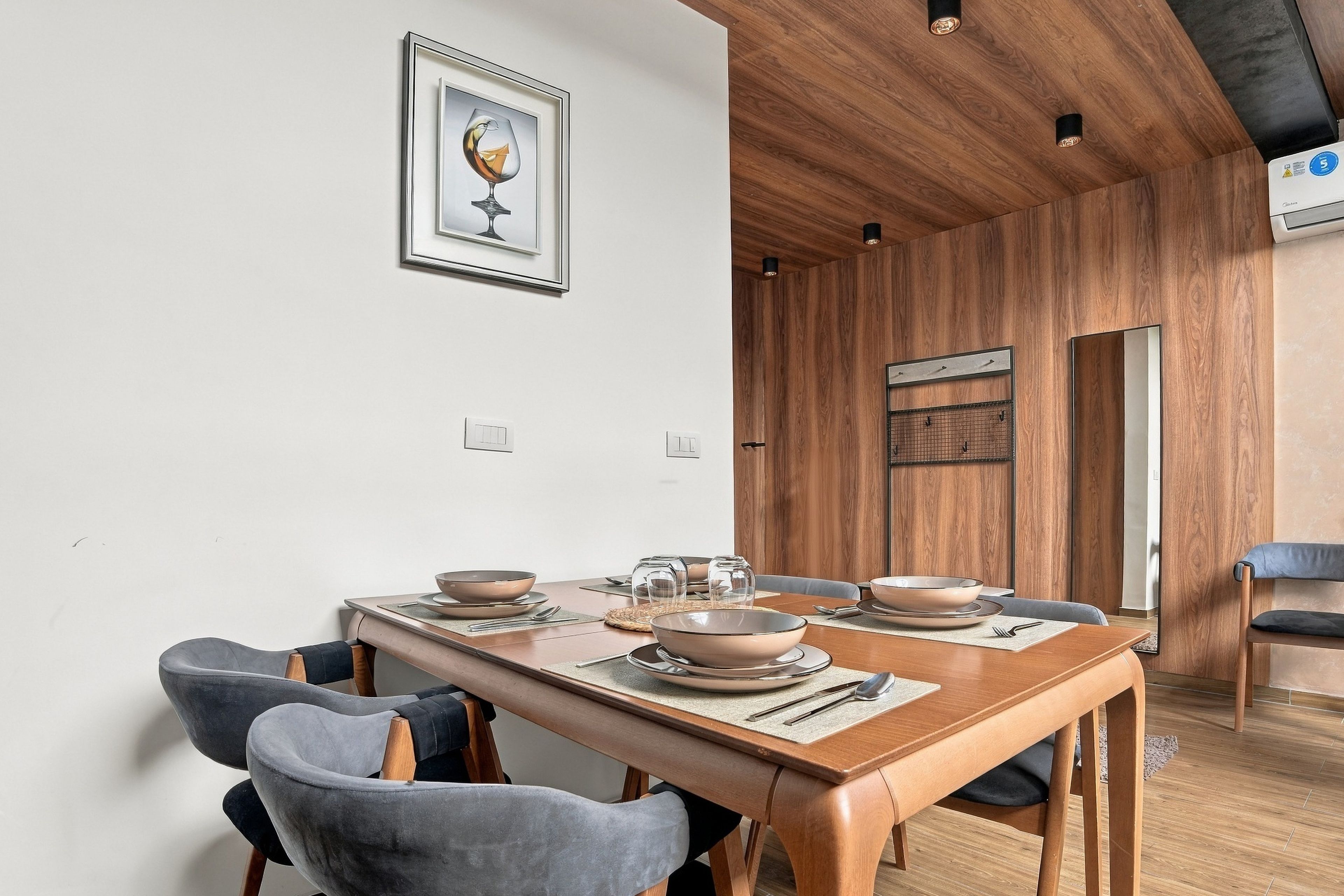 Un'area pranzo con tavolo in legno, sedie rivestite di grigio e una cornice con un'immagine appesa al muro.