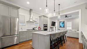 A modern kitchen with stainless steel appliances, a central island with bar stools, and pendant lighting.