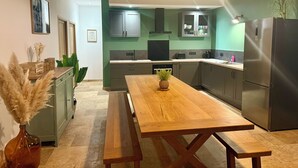 A modern kitchen with a wooden dining table, green cabinets, and a stainless steel refrigerator. - Charming gîte with swimming pool (Rouffignac-Saint-Cernin-de-Reilhac)