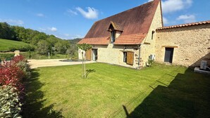 A stone house with a sloped red-tiled roof, a wooden door, and a small window. - Charming gîte with swimming pool (Rouffignac-Saint-Cernin-de-Reilhac)
