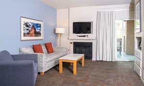 Relax in this stylish living room with a sofa, coffee table, and armchair, perfect for unwinding by the fireplace or enjoying the view from the sliding glass door.