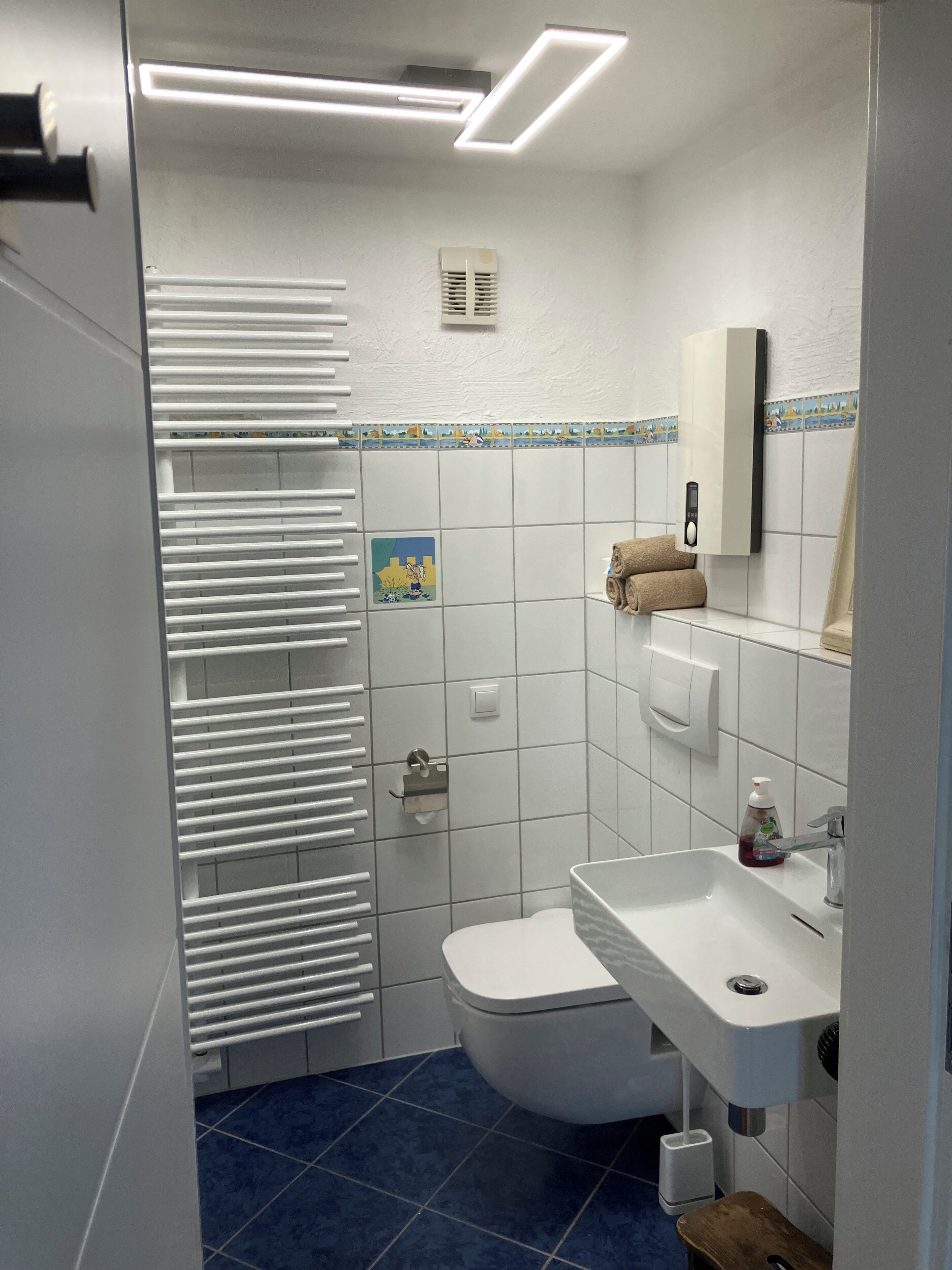 A bathroom with a toilet, sink, towel rack, and a shower area.