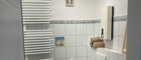 A bathroom with a toilet, sink, towel rack, and a shower area.