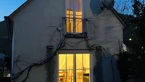 Una casa de dos pisos con un balcón y un ventanal grande.