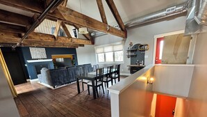 Eine moderne Küche mit Holzbalken, einem Essbereich und einer Treppe mit rotem Akzent.