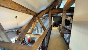 Eine schmale Holztreppe mit Metallgeländern, die zu einer oberen Etage führt.