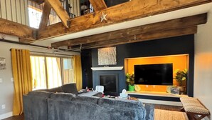 Ein modernes Wohnzimmer mit einem großen Ecksofa, einem Flachbildfernseher und einem Kamin.