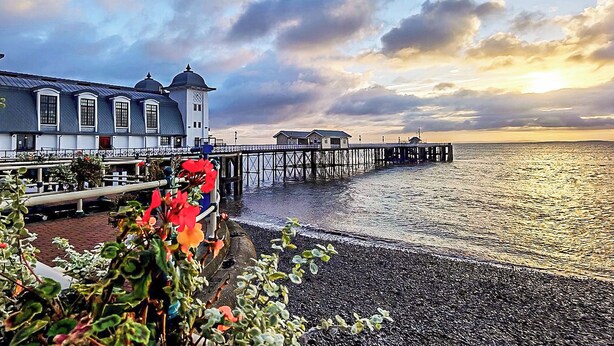 A waterfront building with a pier extending into the water, a clear sky, and a sunset. - 2 bedroom accommodation in Penarth (Penarth)