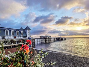 A waterfront building with a pier extending into the water, a clear sky, and a sunset. - 2 bedroom accommodation in Penarth (Penarth)