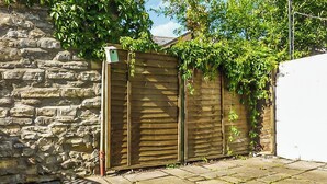 A stone wall, a wooden fence, and a paved patio area. - 2 bedroom accommodation in Penarth (Penarth)