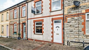 A row of terraced houses with brick and plaster exteriors, a white door, and a satellite dish. - 2 bedroom accommodation in Penarth (Penarth)