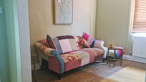A cozy living room with a sofa, a small table, and a painting on the wall. - 2 bedroom accommodation in Penarth (Penarth)