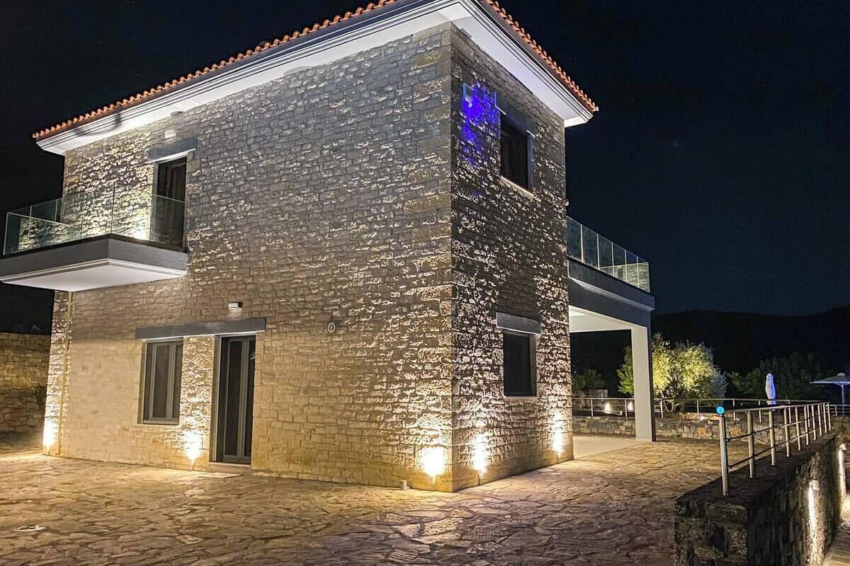 A stone building with a balcony, illuminated by exterior lights.