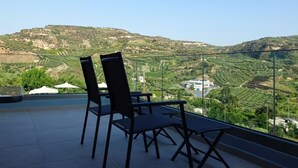 Una terrazza con due sedie e un tavolo, affacciata su un paesaggio collinare con edifici in lontananza.