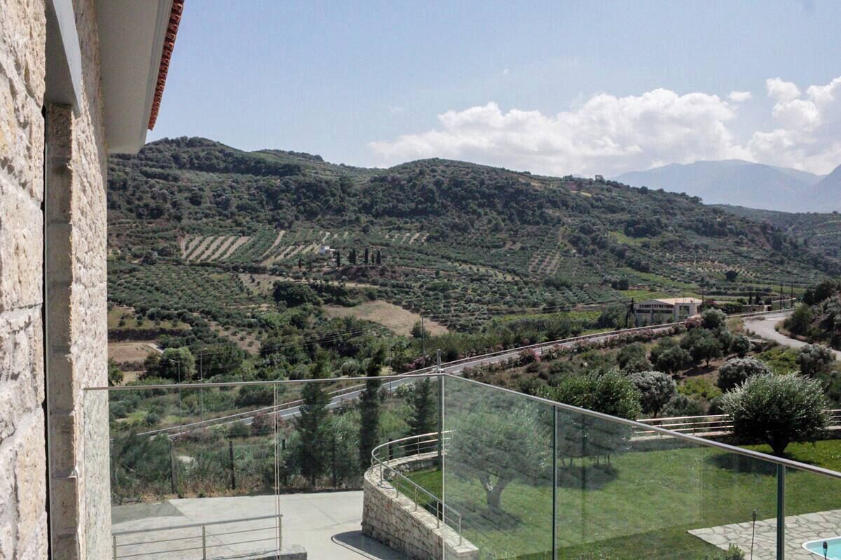 A balcony with a clear view of a vineyard and distant hills.