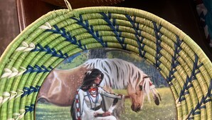 Una cesta tejida con una pintura de una mujer nativa americana y un caballo.