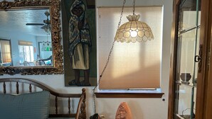 Un dormitorio con cama de madera, una mesita de noche con un florero de cerámica, un cuadro en la pared y una lámpara colgante.