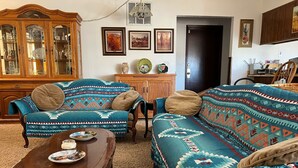Una sala de estar con dos sofás estampados, un mueble de madera y una mesa de comedor con un plato y una vela.
