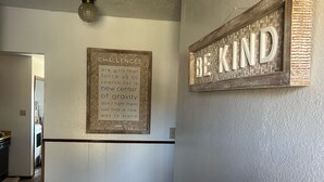 Un pasillo con una cita inspiradora en la pared, un tapete y una puerta que da a otra habitación.