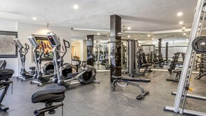 Un gimnasio moderno con diversos equipos de cardio y entrenamiento de fuerza, incluyendo cintas de correr, elípticas y máquinas de pesas.