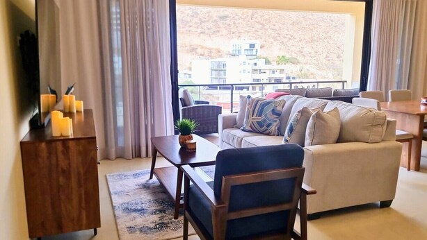 Una sala de estar moderna con un sofá, una mesa de centro y vistas a una colina.