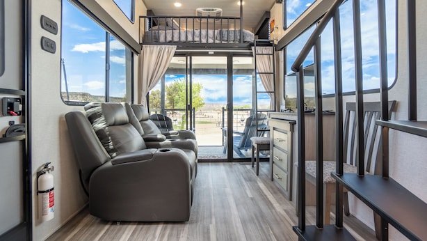 Un intérieur de camping-car moderne doté d’un espace de vie modulable, d’une kitchenette et de grandes fenêtres offrant une vue panoramique.
