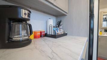 A kitchen with a coffee maker, storage containers, and utensils on the counter.