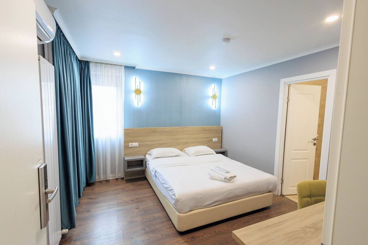 Un dormitorio moderno con una cama grande, mesitas de noche, un radiador y una puerta.
