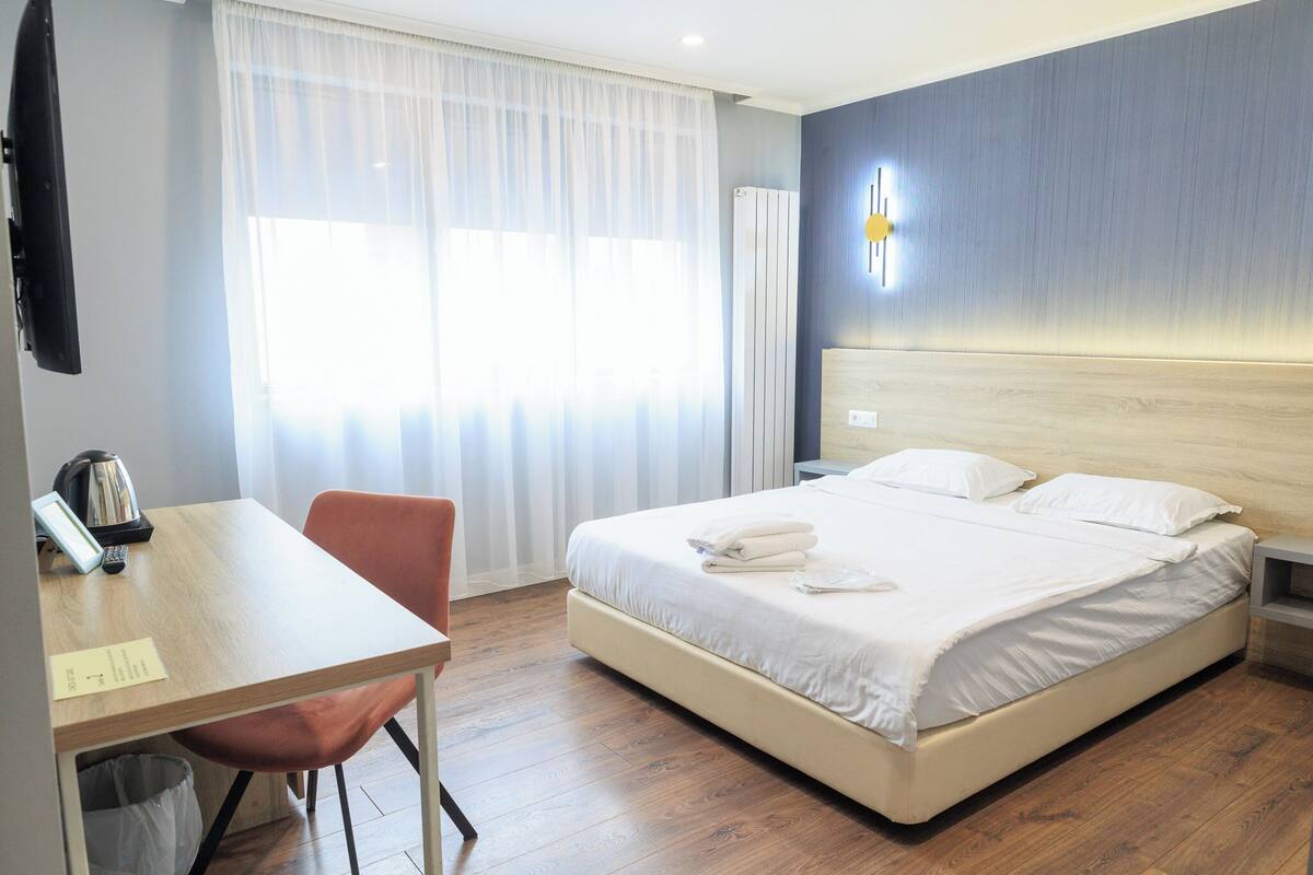 Una habitación de hotel con cama, escritorio, silla y televisión.