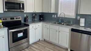 Una cocina moderna con armarios blancos, electrodomésticos de acero inoxidable y salpicadero de azulejos.