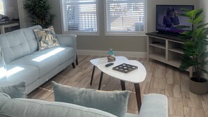 Una sala de estar con un sofá azul claro, una mesa de centro y un televisor sobre un mueble.