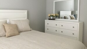 Un dormitorio con cama, cómoda y espejo.