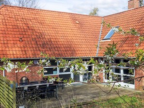 A house with a red-tiled roof, a brick exterior, and a patio area with outdoor furniture.