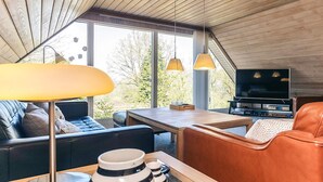 Ein modernes Interieur mit einer Couch, einem Couchtisch, einem Fernseher und einem großen Fenster.