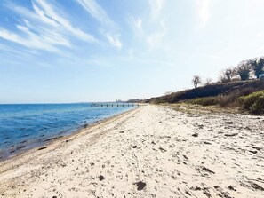 A beach with a clear sky, a wooden pier extending into the water, and sparse vegetation on the right. - 4 Star Holiday Home in Asperup (Middelfart)