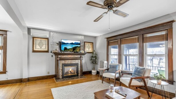 Un salon avec une cheminée, un téléviseur et un ventilateur de plafond.