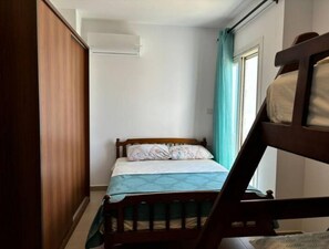 A small, narrow room with a single bed, a wooden wardrobe, and a window with curtains. - Enjoy a Greek flavor in Egypt's north coast overlooking the Mediterranean sea (Marsa Matrouh Governorate)