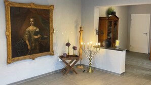 A hallway with a large framed painting, a candelabra with lit candles, and a wooden cabinet with glassware. - Vacation home Mosel-Wohnen I in Ferienland Cochem -balcony, sauna, garage (Bruttig-Fankel)