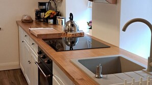 Una cocina con armarios de madera, un lavamanos y una encimera con varios objetos.